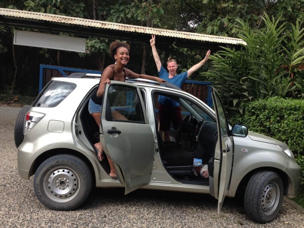 travel couple celebrating outside their rental car for a road trip