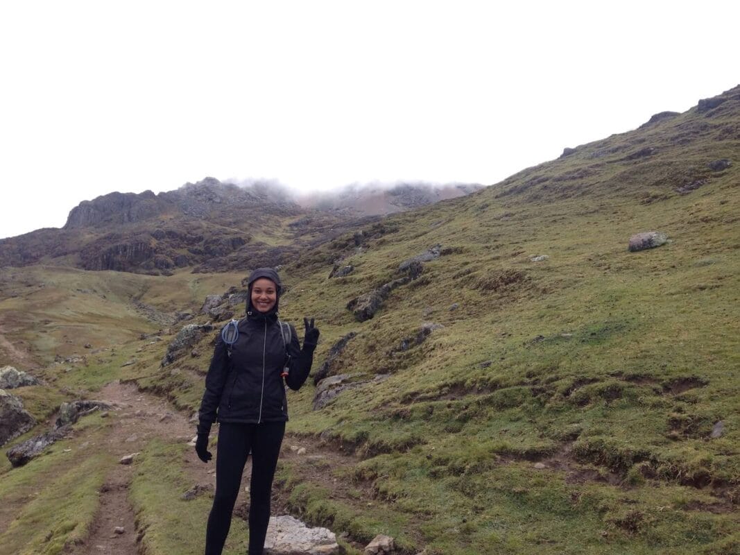 Happy hiker waving on cold rainy day in mountains