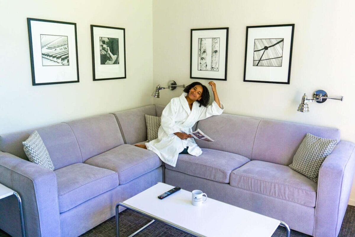 woman sitting on sofa couch in bathrobe inside hotel apartment suite living room