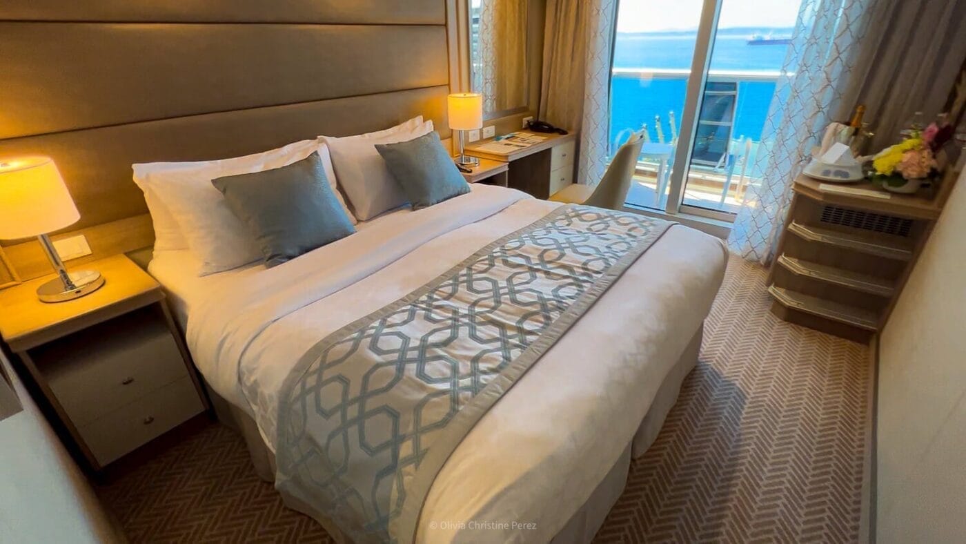 queen size bed, desk, and nightstand in balcony stateroom