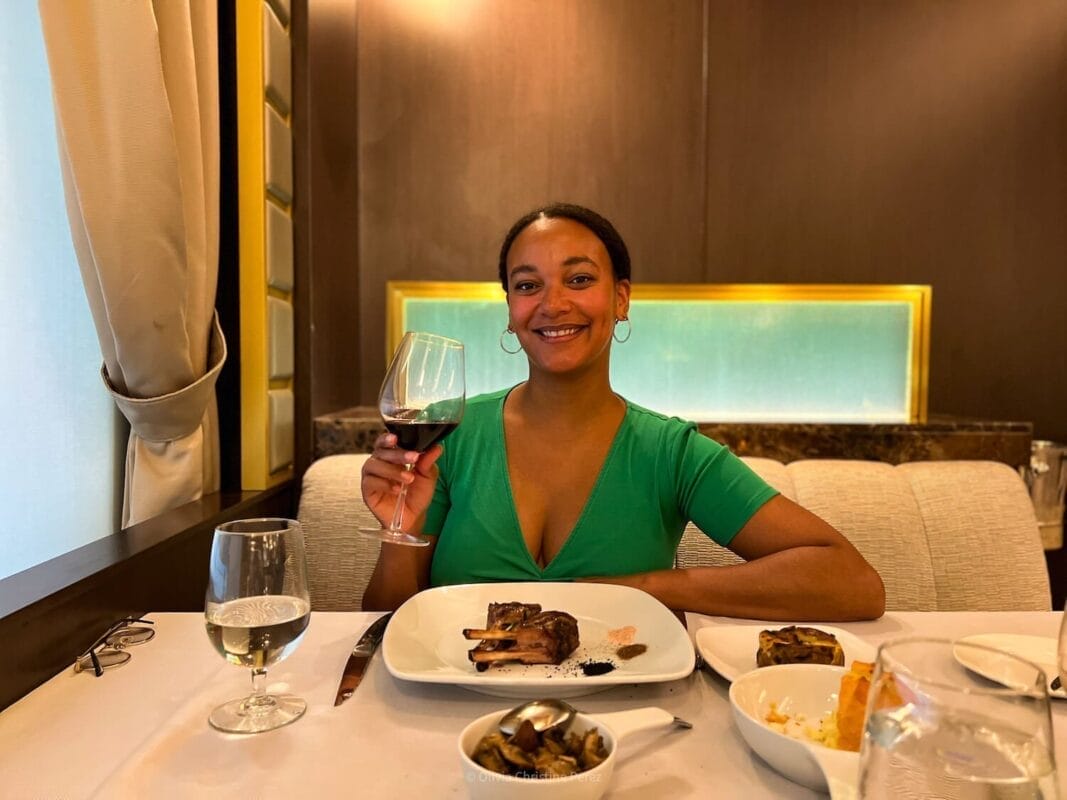 woman drinking red wine and eating steak in restaurant