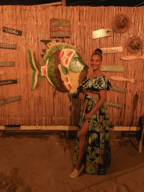 Standing in front of a Bajan restaurant entrance with a large fish sculpture