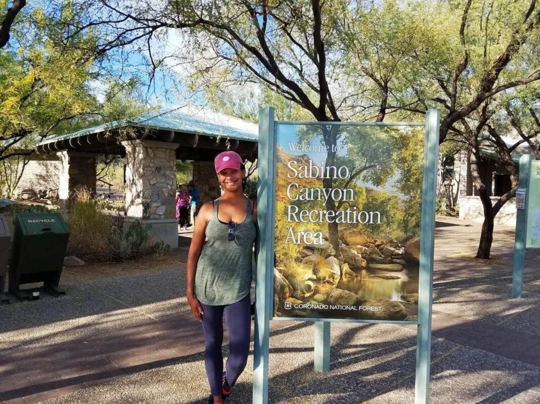 Standing in front of a park sign that says Sabino Canyon Recreation Area