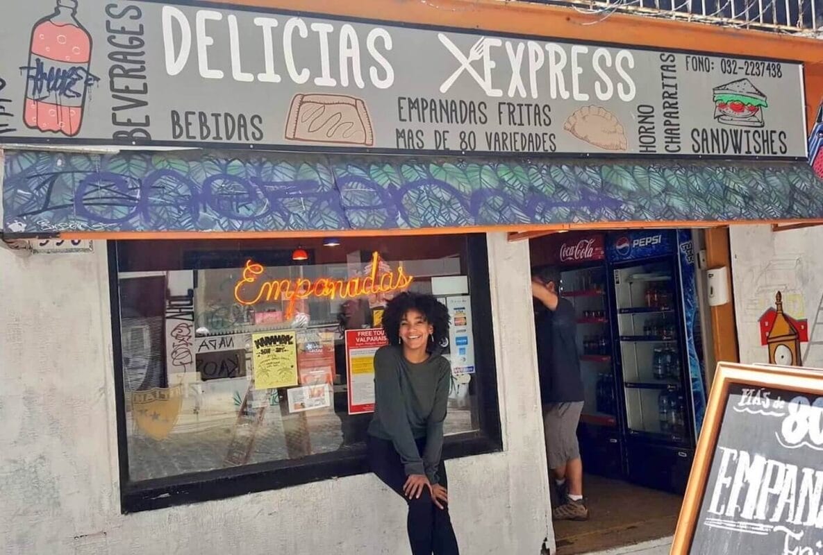 Sitting in front of an empanada bakery that says "Delicias Express: empanadas fritas. Mas de 80 variedades"