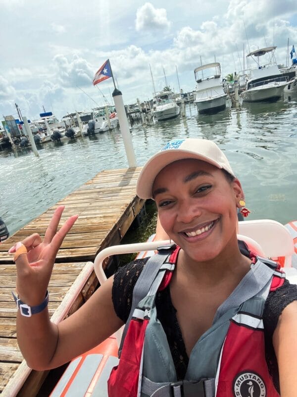 smiling in a mini speed boat at the dock with flag waving behind the boat