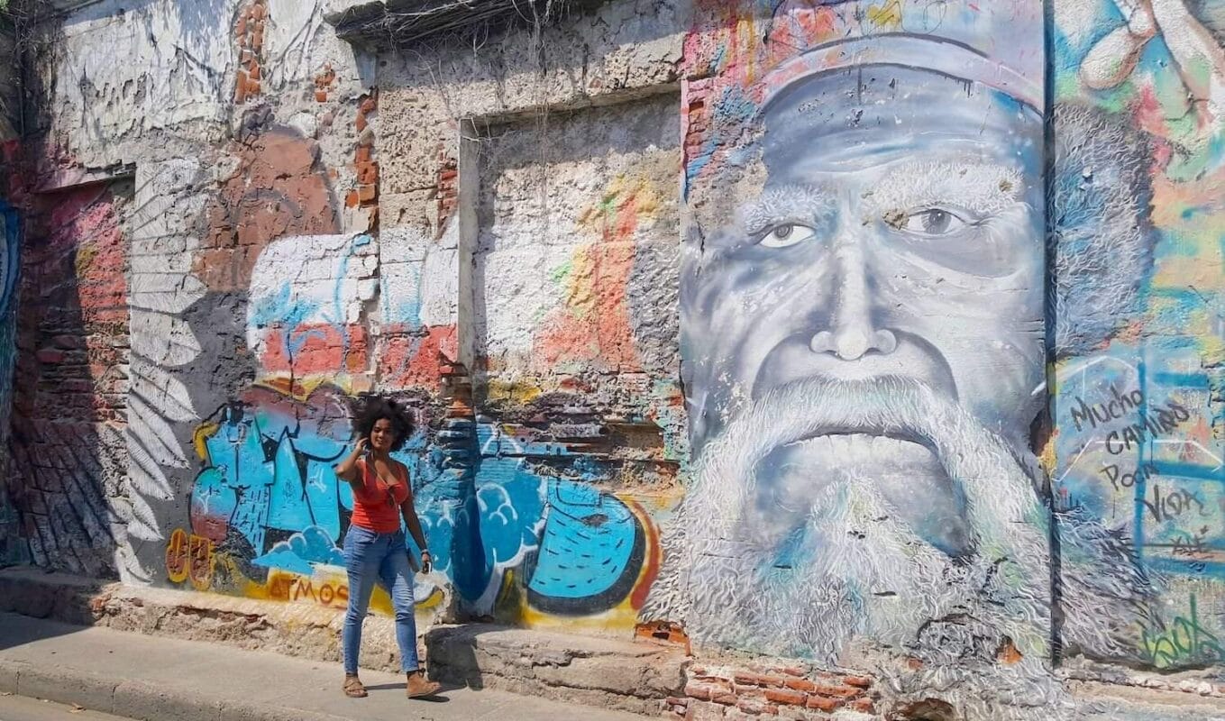 black tourist with afro hair walking along street art mural in Cartagena