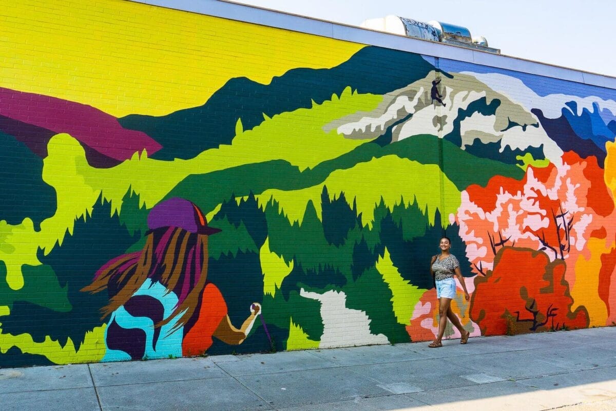 walking past a colorful street mural with female hiker trekking through Vermont's green mountains