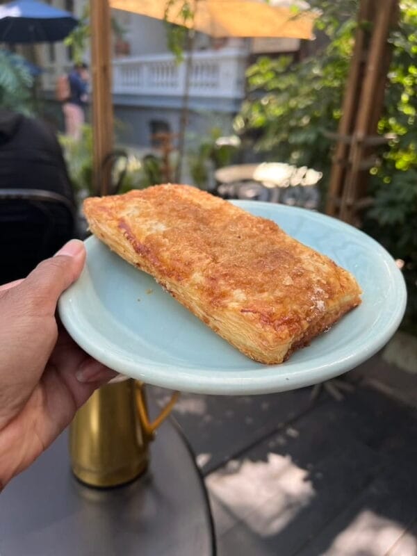 hand holding up a pastry in outdoor bistro seating