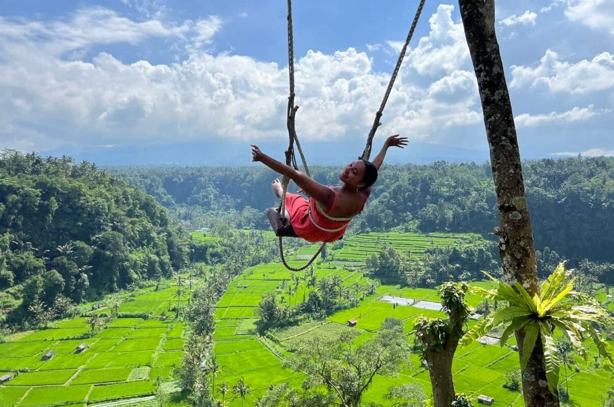 woman swinging over rice fields