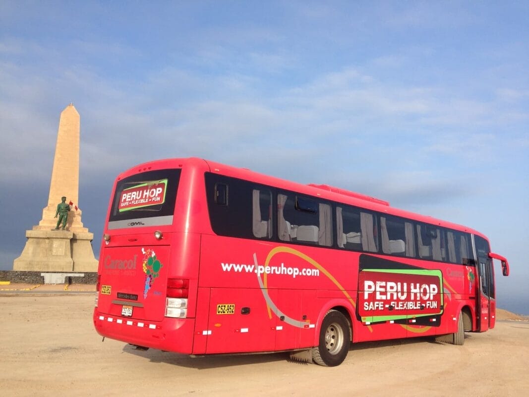 The red bus stops next to the statue. The bus has