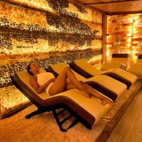 woman laying on lounge chair in a spa treatment room with salt walls and floors