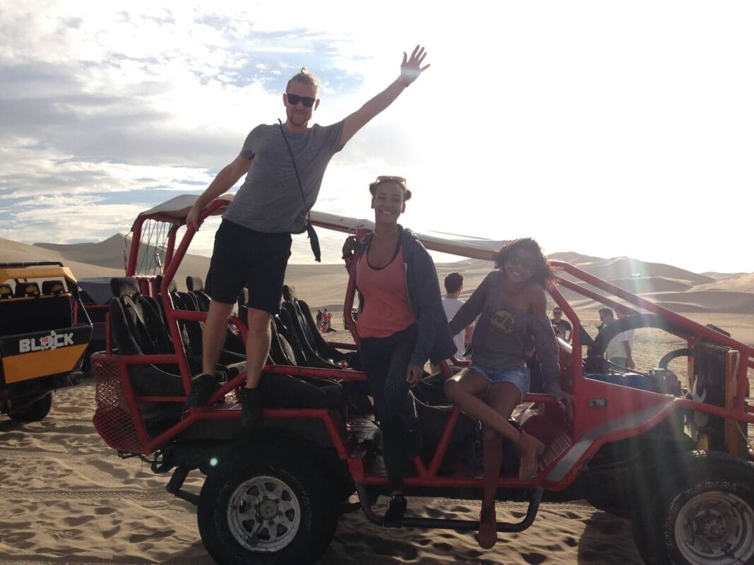 3 tourists riding a dune buggy in the desert