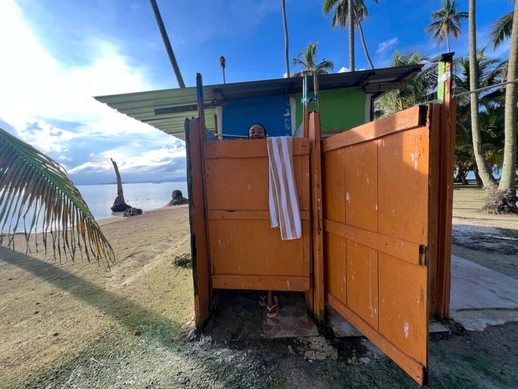 tourist in outdoor shower, peeking over the wooden door