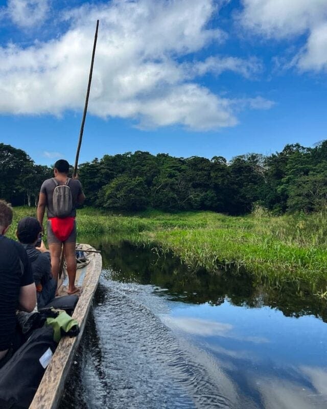 indigenous man rowing wooden boat