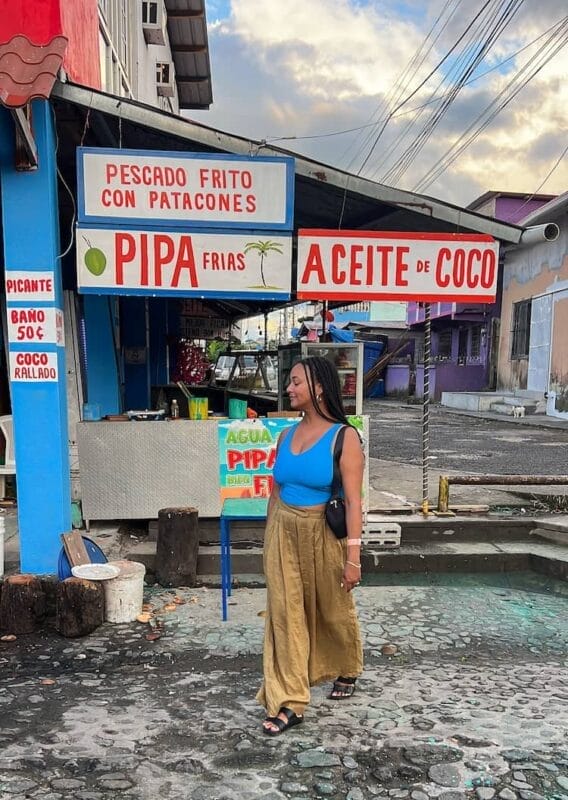 afro latina tourist walking past food kiosk that says pescado frito con patacones