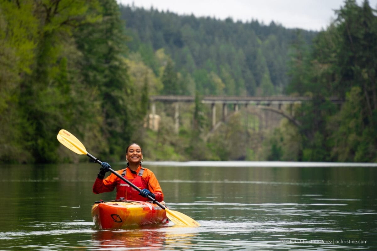 Single kayaking, bridge in the background and forest